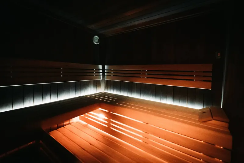 Sauna s dřevěnými lavicemi a nepřímým světlem